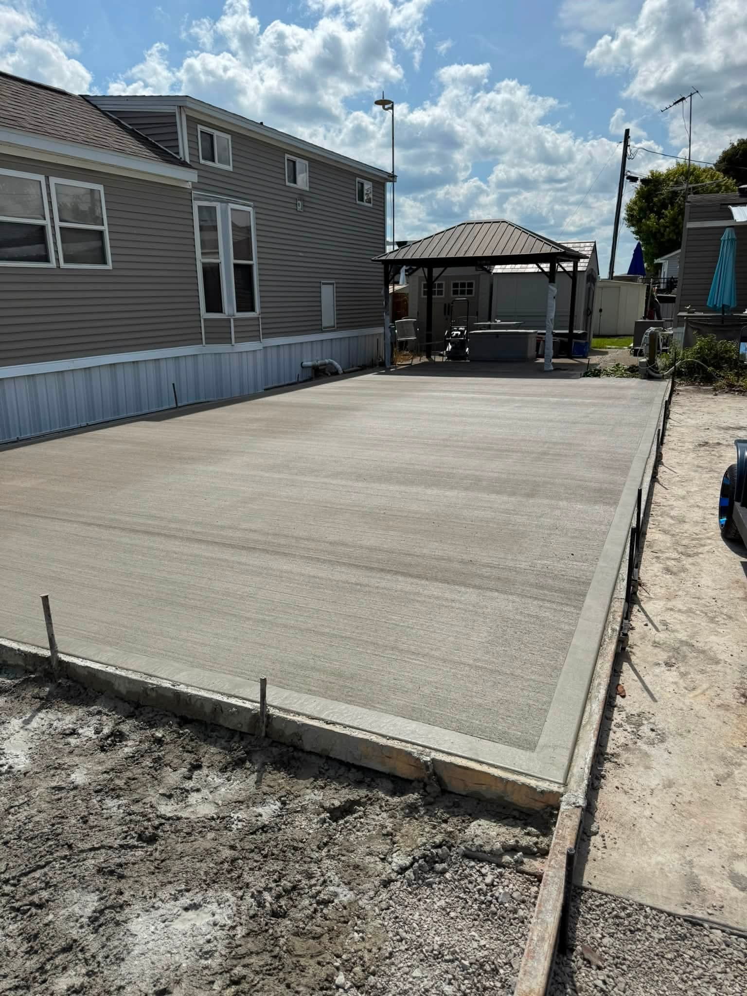 Fresh concrete flatwork beside a home, with edge forms in place.
