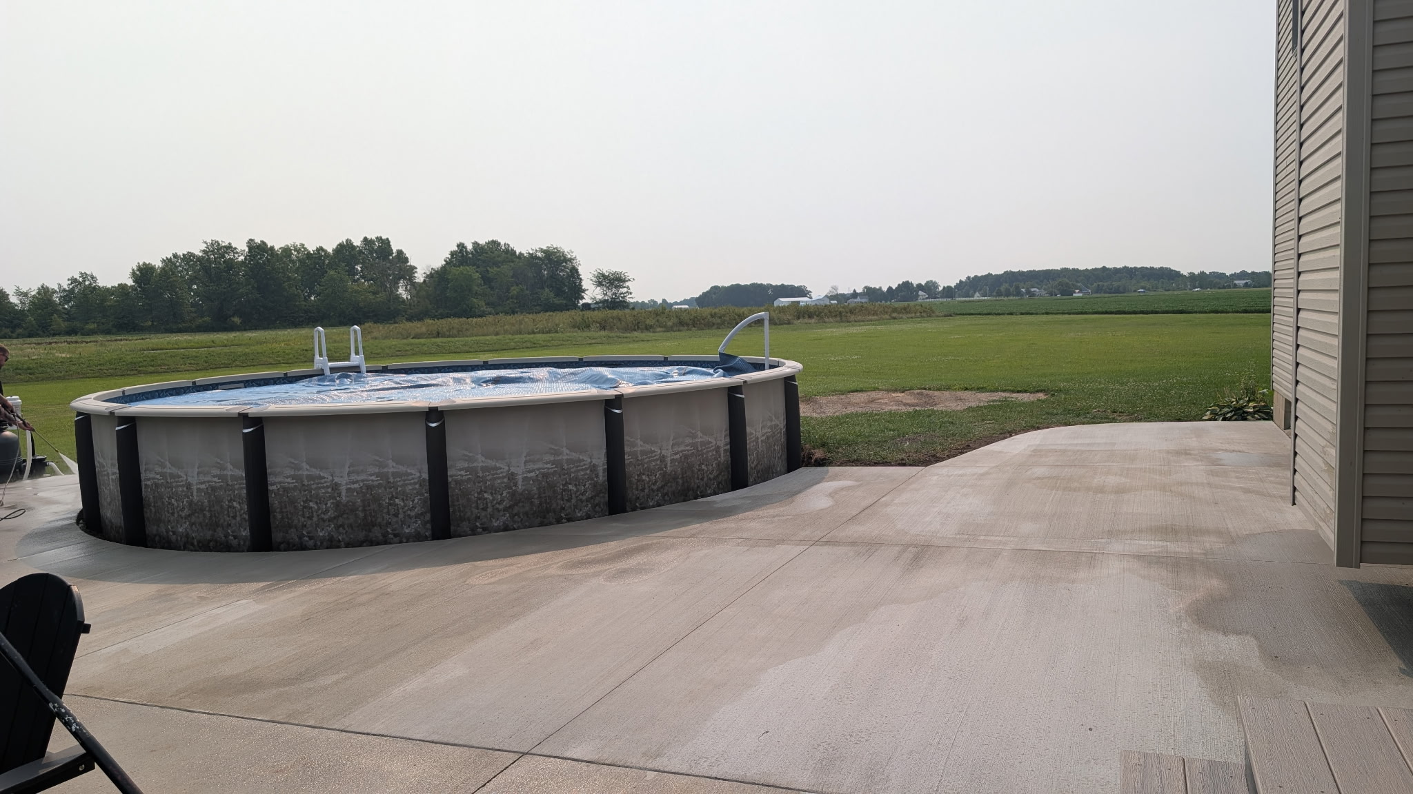 Wide view of a concrete patio and walkway around an above-ground pool.