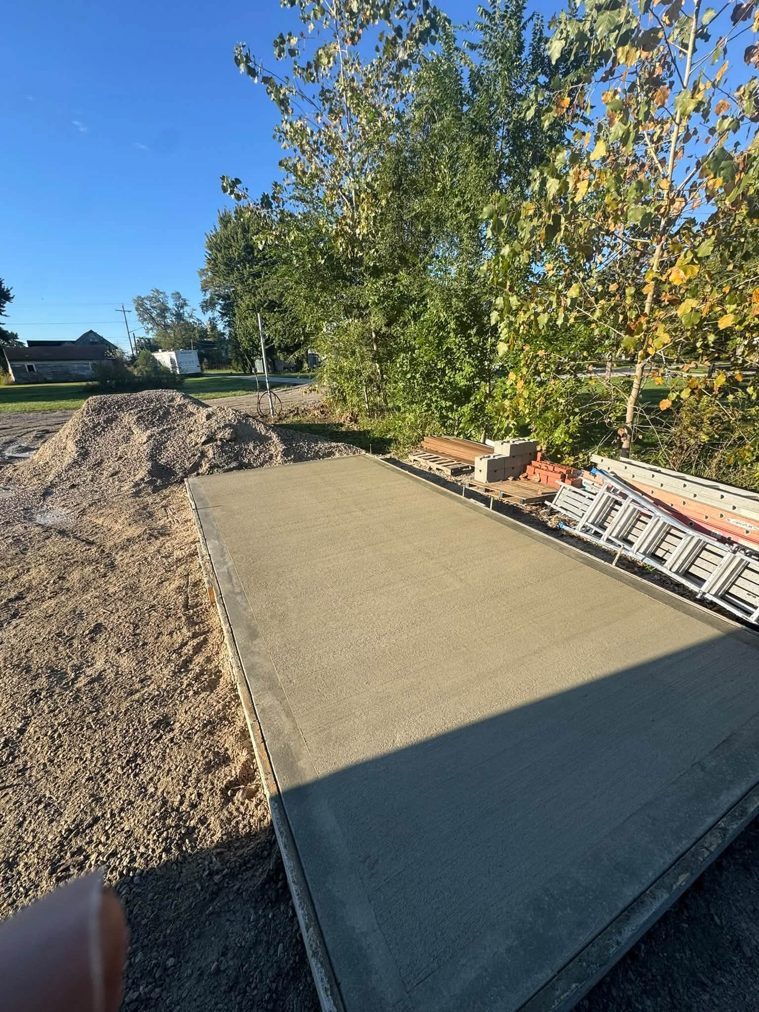 Rectangular concrete slab with forms and surrounding aggregate.